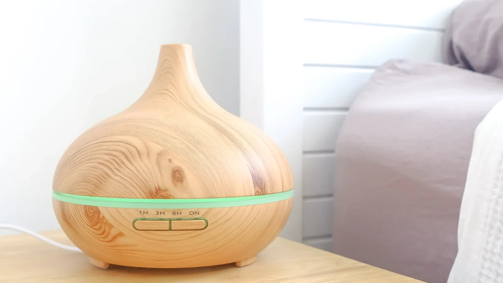 Ultrasonic essential oil diffuser releasing a cool mist in a cosy bedroom