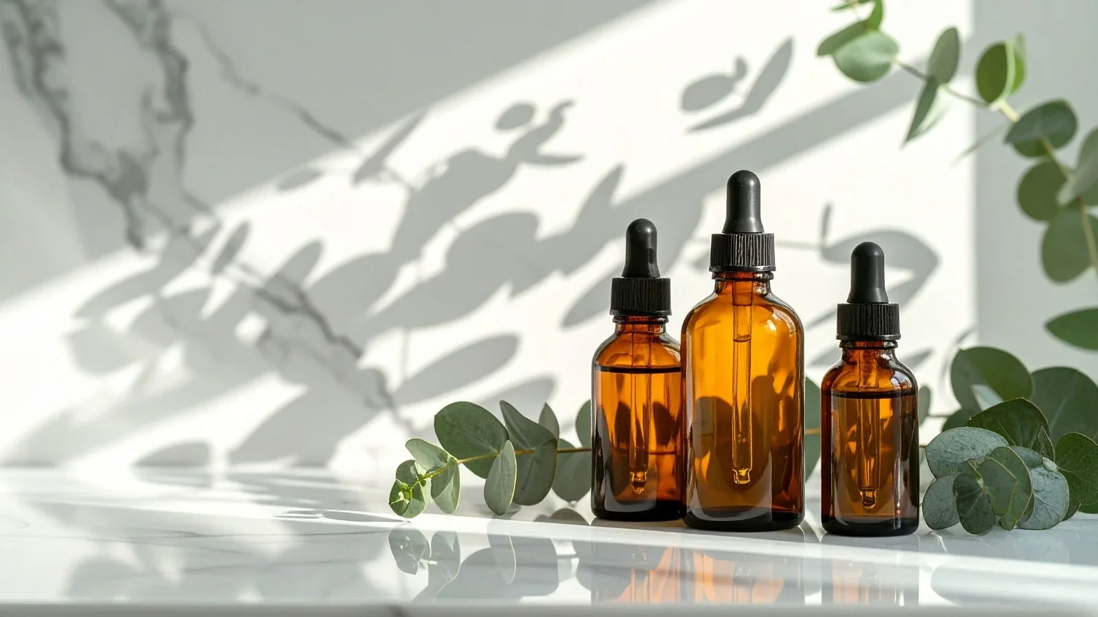 Amber dropper bottles of eucalyptus essential oil beside fresh eucalyptus leaves