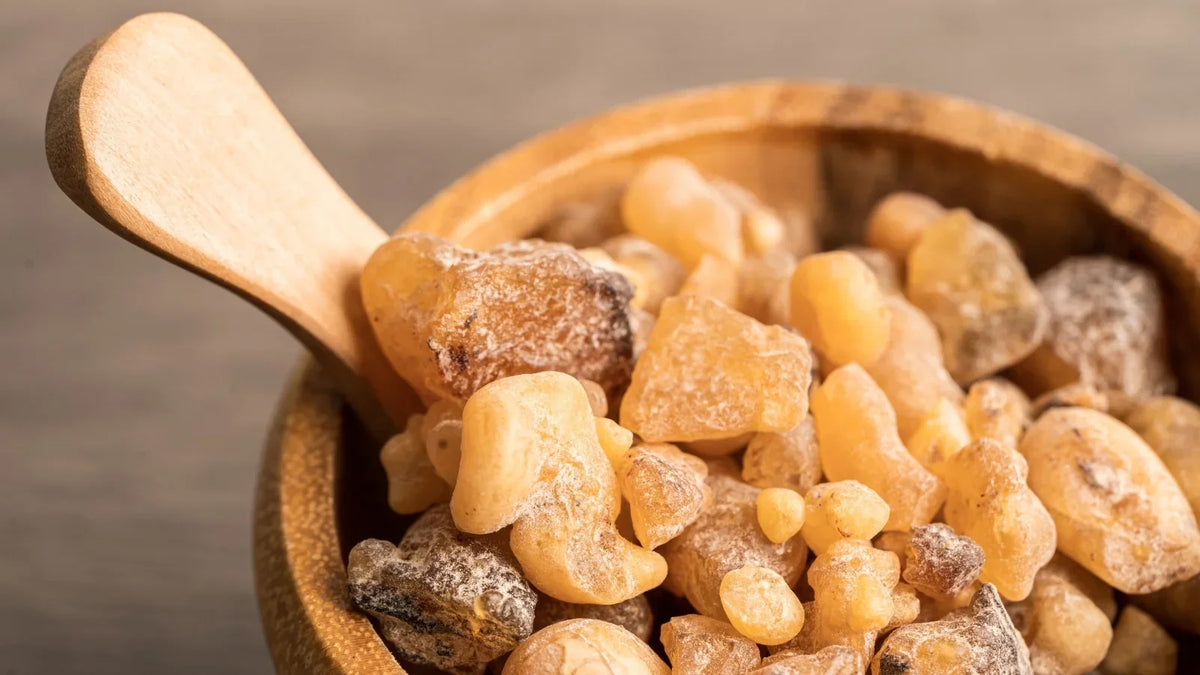 Amber bottle of frankincense essential oil beside frankincense resin
