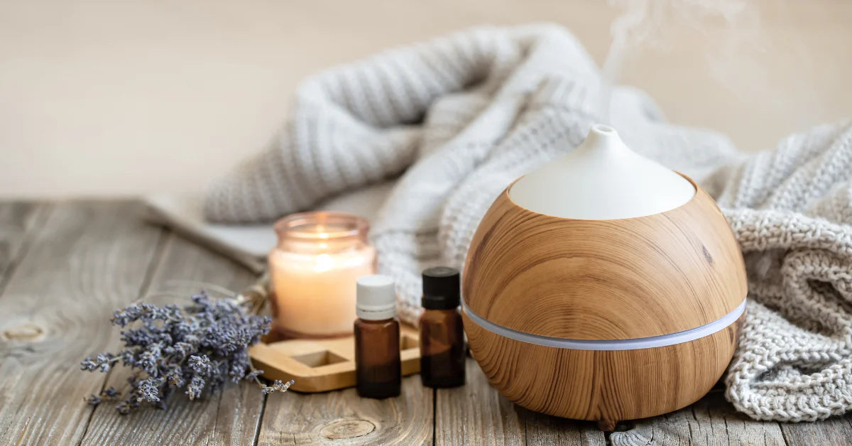 Essential oil bottles with diffuser, carrier oil and roller blend arranged with fresh botanicals for beginners