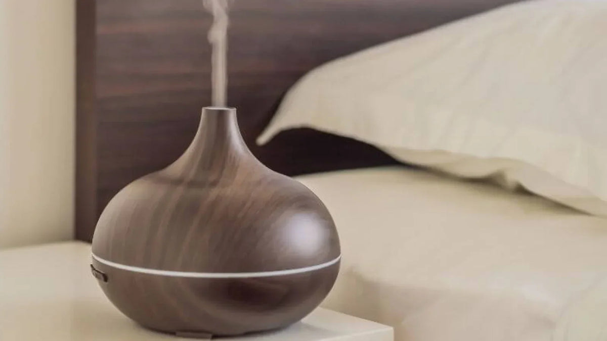 Wood-grain ultrasonic oil diffuser releasing a fine aromatic mist on a shelf at home