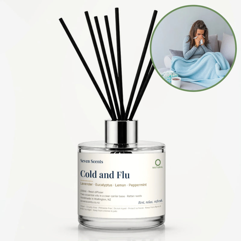 Cold and Flu Reed Diffuser by Seven Scents - glass bottle with a woman wrapped in a blue blanket on a sofa