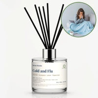 Cold and Flu Reed Diffuser by Seven Scents - glass bottle with a woman wrapped in a blue blanket on a sofa