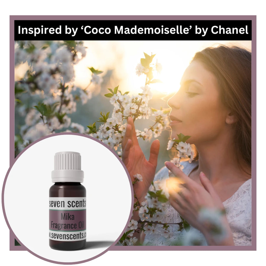 Woman smelling flowers with a bottle of Seven Scents Mika Fragrance Oil inset, inspired by Coco Mademoiselle by Chanel.
