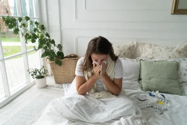 Sick woman in bed blowing her nose